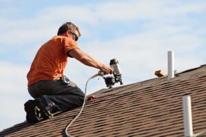 Homeowner inspecting clear gutters and a downspout directing rainwater away from a house